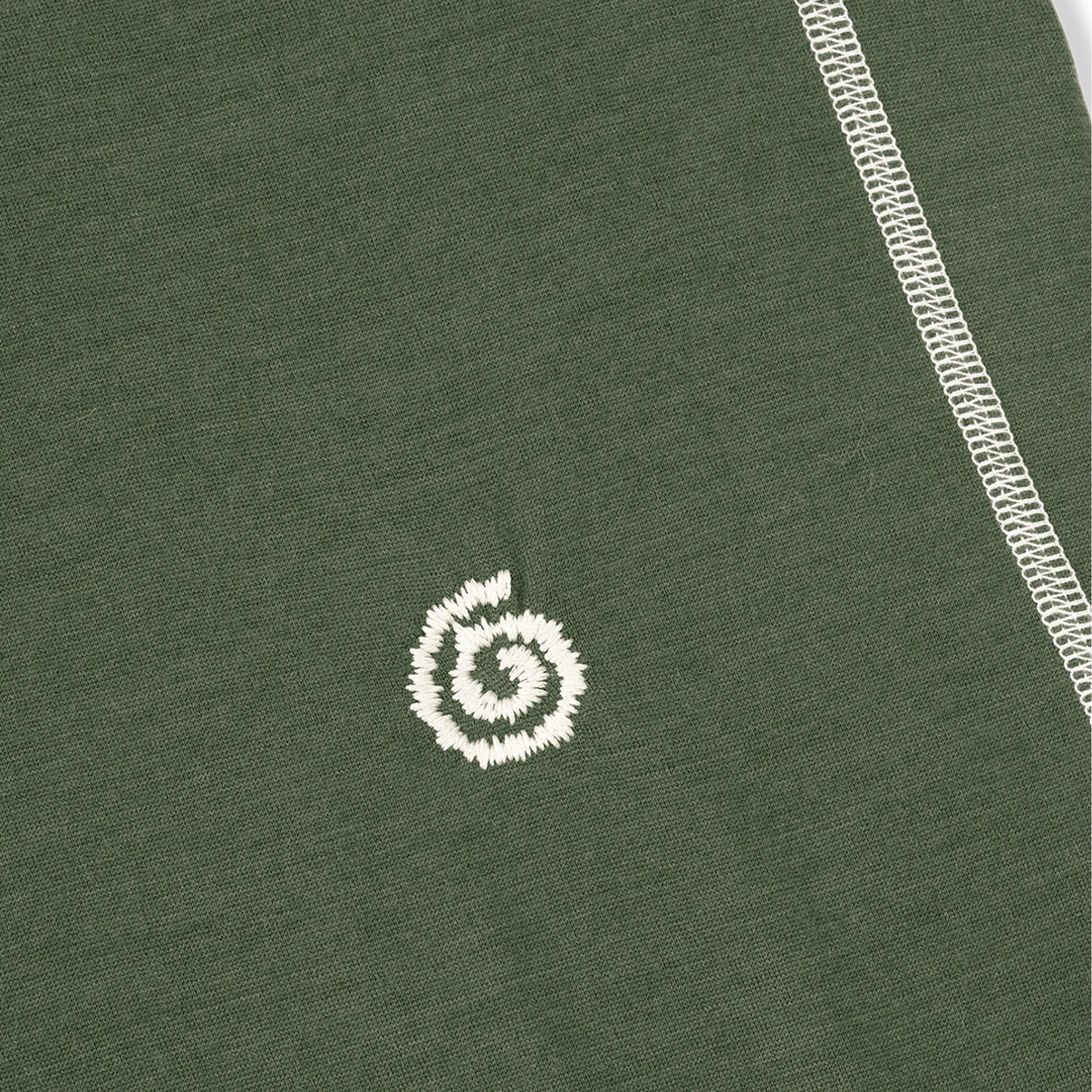 Close-up of a green fabric with a white embroidered logo on a plain background