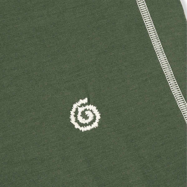 Close-up of a green fabric with a white embroidered logo on a plain background
