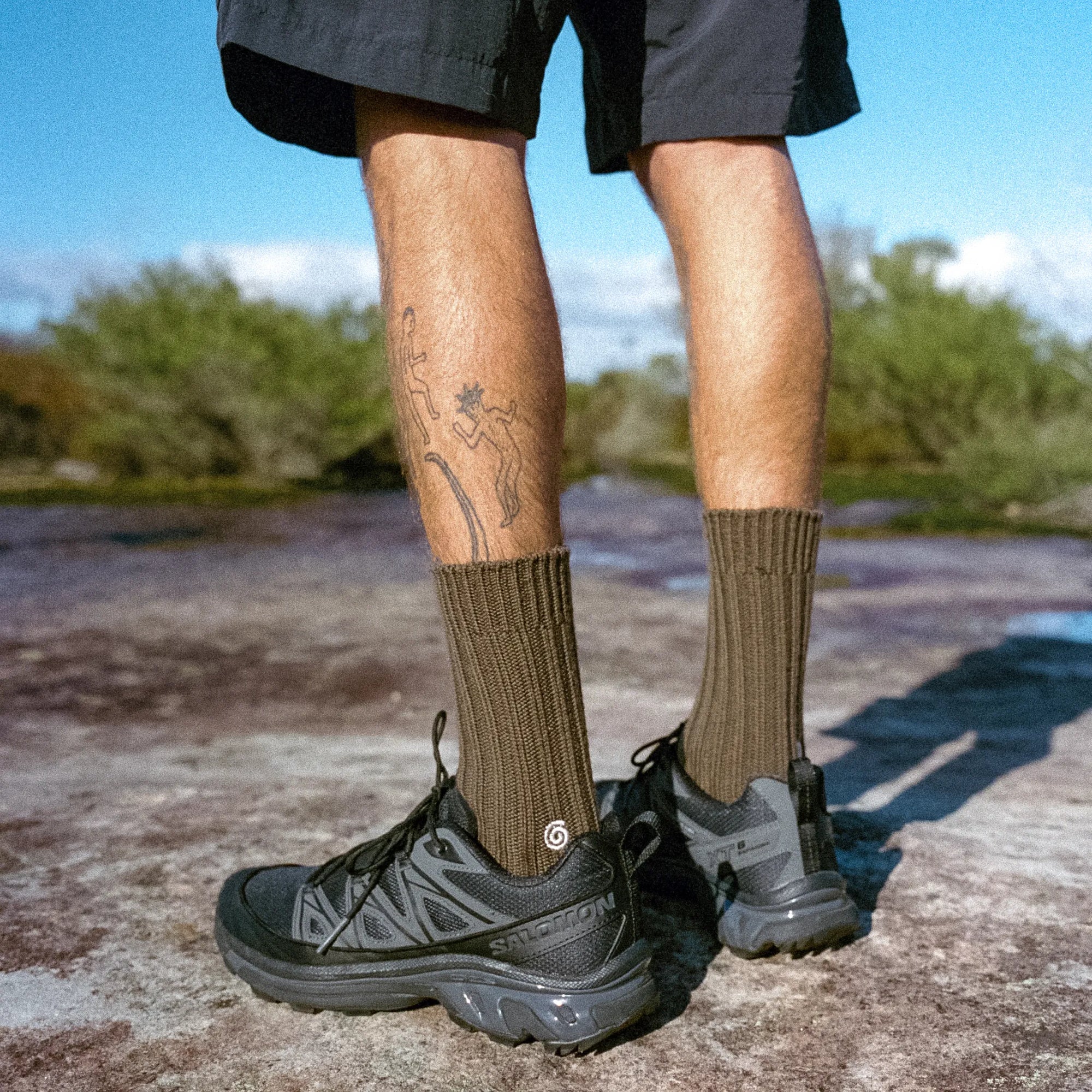 Person wearing brown hiking socks and black hiking boots on a natural outdoor setting.