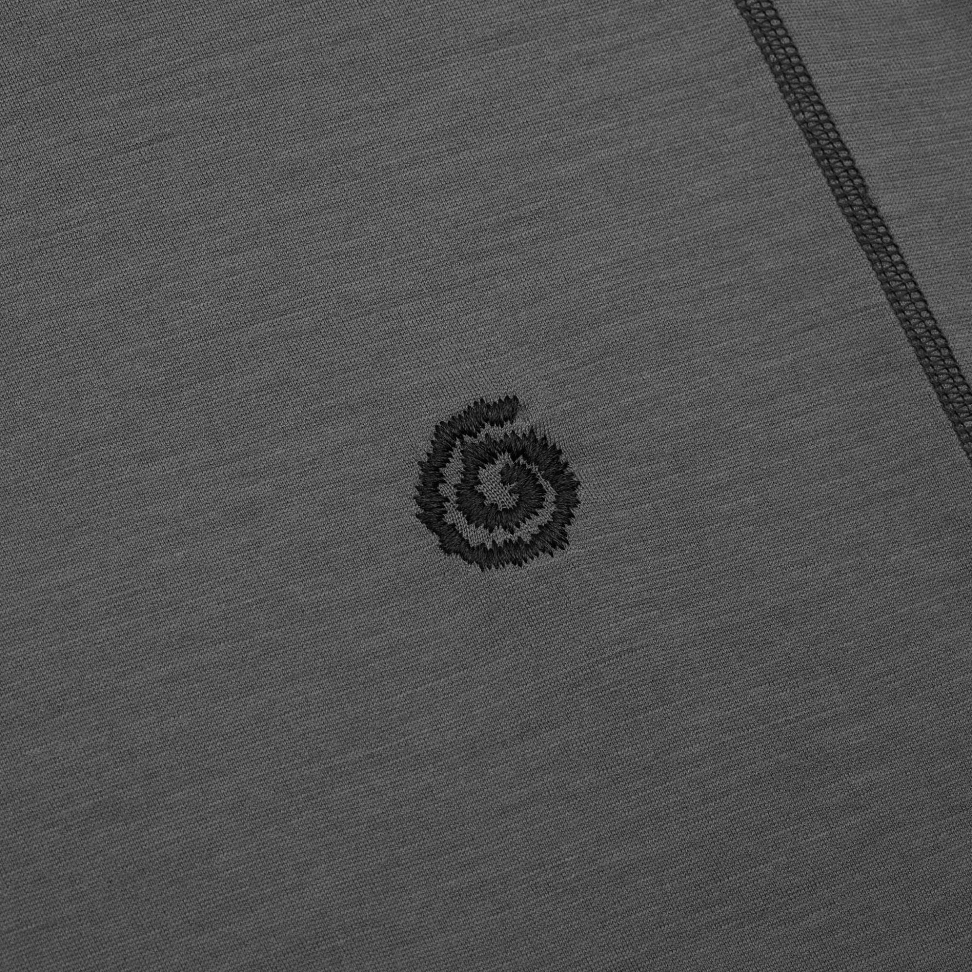 Close-up of a gray fabric with a small embroidered logo on a gray background