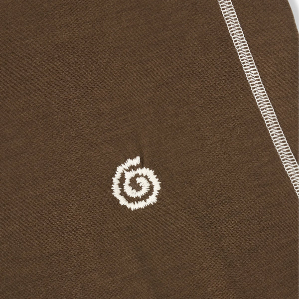 Close-up of a brown fabric with a white embroidered logo on a plain background