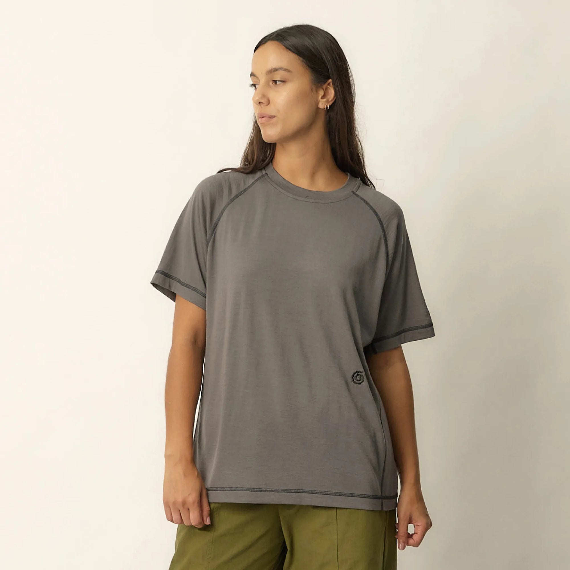 Person wearing a gray t-shirt and green pants on a plain background