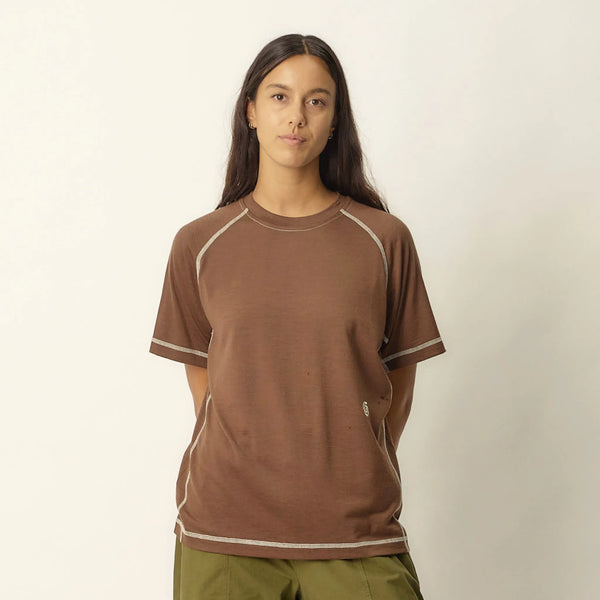 Person wearing a brown t-shirt with white trim on a white background