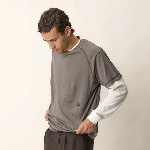 Man wearing a gray t-shirt with a white undershirt on a white background