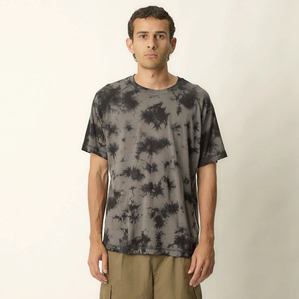 Man wearing a tie-dye t-shirt against a plain background