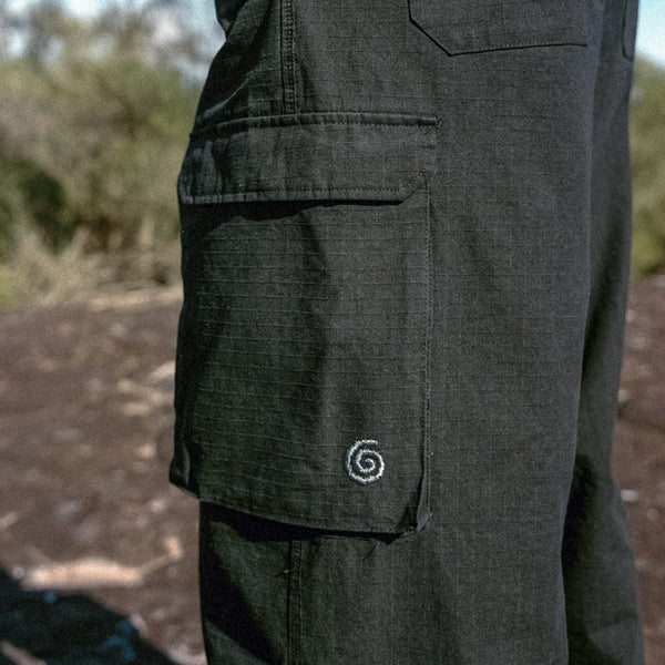 Black Cargo pants with a spiral emblem on the pocket against a natural background
