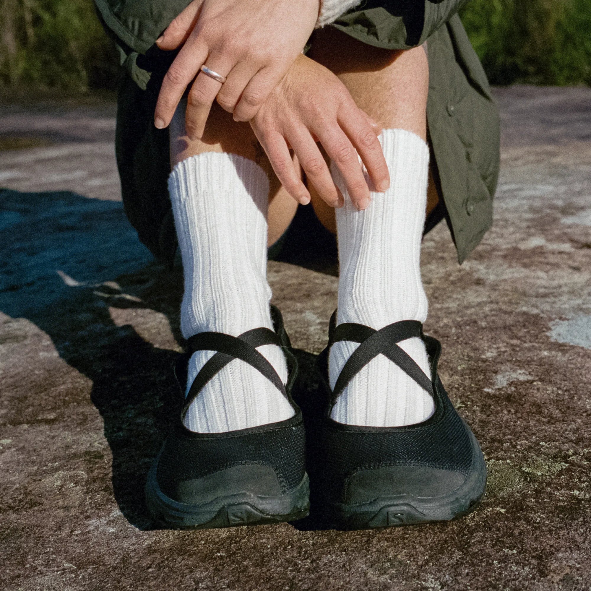 Person wearing black shoes with white socks on a concrete surface